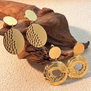 Vintage gold plated geometric earrings with hammered texture on a dark wooden branch