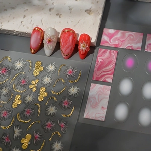 Dettaglio di adesivi per unghie con fiori 3D in rilievo, tocchi dorati e marmo rosa