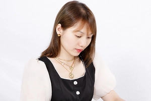 Model wearing a layered golden stainless steel necklace set with round pendant and studs