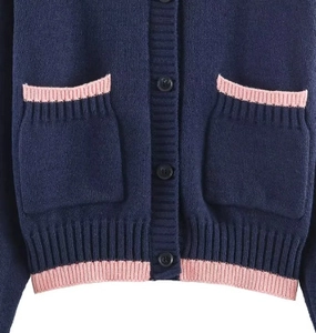 Détail du cardigan en maille bleu foncé avec bordure côtelée rose sur les poches