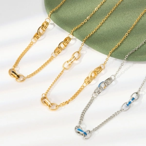Close-up of gold and silver steel chains with blue and black enamel details on white surface