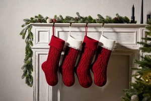 Close-up of four red and white knitted Christmas stockings hanging on a festive fireplace