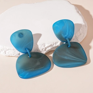 Vue macro de boucles d'oreilles en résine bleue marbrée sur un socle en pierre