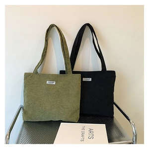 Detail of corduroy tote bags in army green and black on a minimalist silver rack