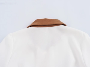 Detailed close-up of brown corduroy collar on a white dress with refined stitching