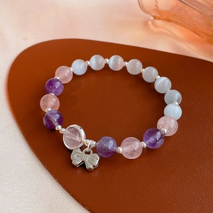 Detail of beaded bracelet with purple amethyst, pink quartz, and bow charm on leather