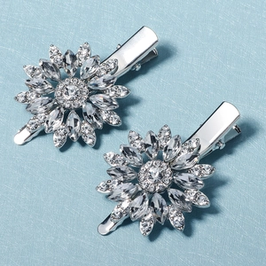 Elegant pair of silver floral rhinestone hair clips with sunflower design on blue surface