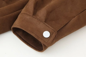 Detail van bruine suède jas manchet met witte knoop en fijne stiksels