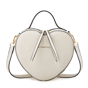 Detail of white heart-shaped handbag featuring textured faux leather and golden logo
