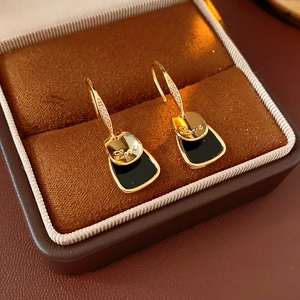 Dettaglio di orecchini quadrati placcati in oro con intarsio nero e incisione Love in scatola