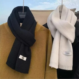 Detail shot of soft knit scarves in black and white with fringe and FLOWS brand labels