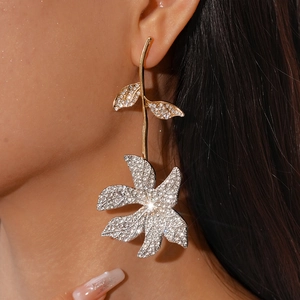 Close-up of elegant gold flower earrings with crystals worn by a model in detail