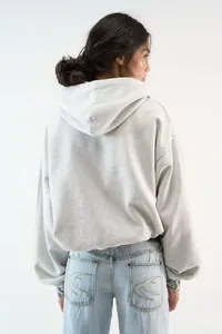 Detail of light gray hoodie and blue jeans with swallow embroidery on the back pocket