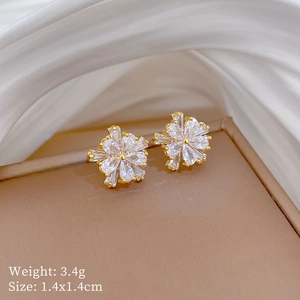 Macro detail of gold flower earrings with zircon inlays and 1.4x1.4cm dimensions