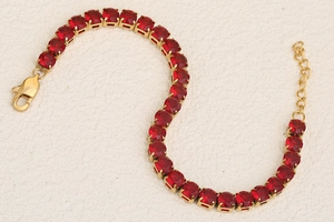 Macro shot of 18K gold plated bracelet with sparkling red cubic zirconia and lobster clasp