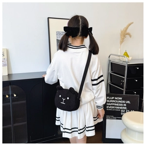 Detail of cute black plush bear shoulder bag with adjustable strap worn by a child