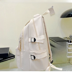 Side view of large cream school backpack showing dual zippers and side strap buckles