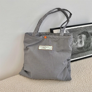 Detail of checkered tote bag with Cheerful Sozakka embroidery and orange snap button