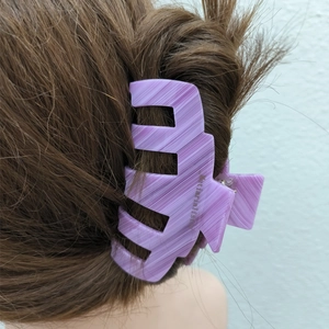 Détail d'une pince à cheveux en acétate violet marbré sur un chignon de cheveux bruns