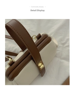 Detail of contrast color handbag showing gold metal twist lock and fine stitching