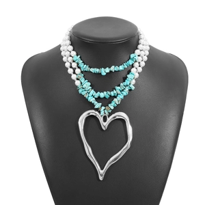 Detail of layered turquoise and pearl necklace with a large silver heart pendant