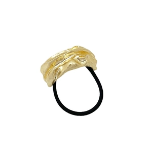 Black elastic hair tie with irregular gold metallic buckle on a clean white background