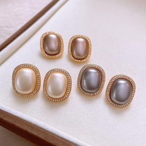 Detailed close-up of vintage oval pearl earrings in jewelry box with gold trim