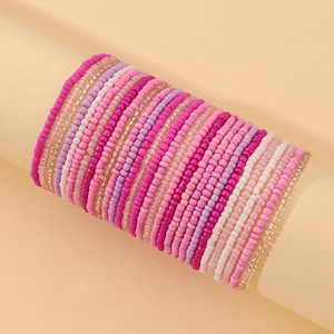Detail of pink and purple beaded stretch bracelet layers on a cylindrical stand