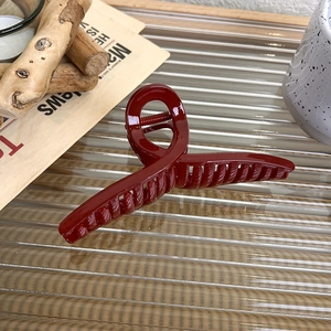 Close-up of a festive deep red hair claw clip on a stylish glass surface with decor