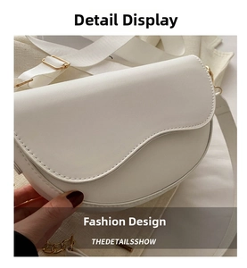 Gros plan d'un sac selle en cuir blanc avec large bandoulière et chaîne dorée