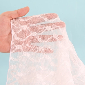 Dettaglio del tessuto in pizzo bianco con motivi floreali traforati per costumi da spiaggia