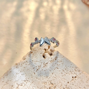 Detail of silver butterfly ring with pink crystals and branch texture on a stone