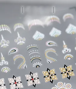Dettaglio macro di adesivi per unghie con rilievo 5D, motivi mandala bianchi e tocchi rossi