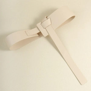 Close-up of a wide beige leather corset belt tied in a minimalist knot on a white surface