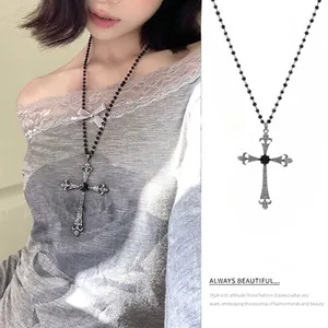 Macro detail of gothic black beaded necklace with ornate silver cross and grey bow
