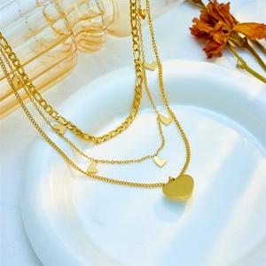 Multilayer gold heart pendant necklace featuring figaro chain and dainty heart charms
