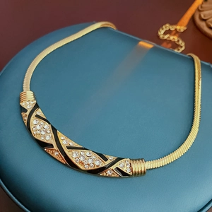 Makro-Detail der goldenen Vintage-Schlangenkette mit Emaille und Kristallen