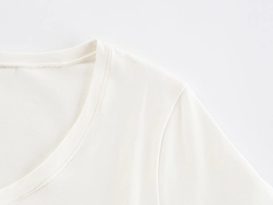 Detailed macro view of the soft knitted fabric texture and fine stitching on the white U-neck tee