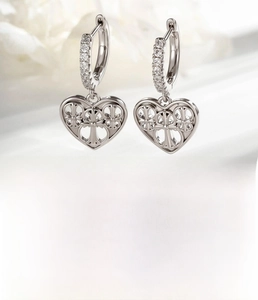 Detail view of silver heart earrings with micro-inlaid zircons and hollow cross pattern