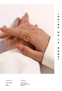 Close-up of gold layered oval intertwined ring on model hand with minimalist aesthetic