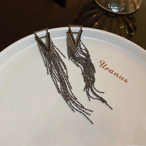 Close-up of geometric triangle tassel earrings with gunmetal bead chains on a display tray