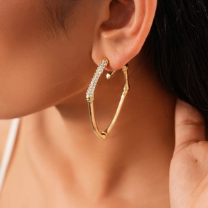 Close-up of elegant gold twisted bamboo earrings with micro-pave crystals on the model