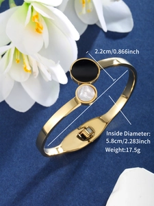 Detail of gold open bangle with black and pearl white circular inlay elements