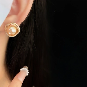 Macro shot of large gold pearl earring with halo of sparkling cubic zirconia details