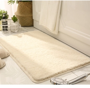 Detailed view of a thick beige absorbent bath mat on a white marble bathroom floor