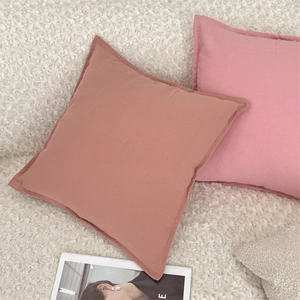Detailed view of dust pink square pillow covers with smooth fabric on soft white texture