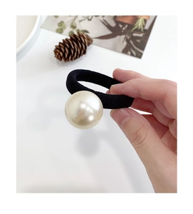 Dettaglio di una grande perla bianca su un elastico per capelli nero a trama fitta