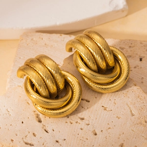 Close-up of chunky gold-plated layered hoop earrings with detailed diagonal texture