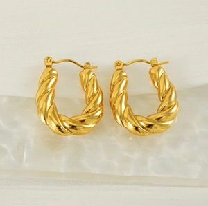 Macro detail of gold-plated twisted hoop earrings with a polished 18K finish