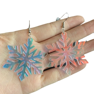 Iridescent acrylic snowflake earrings with silver hooks held in hand on white background